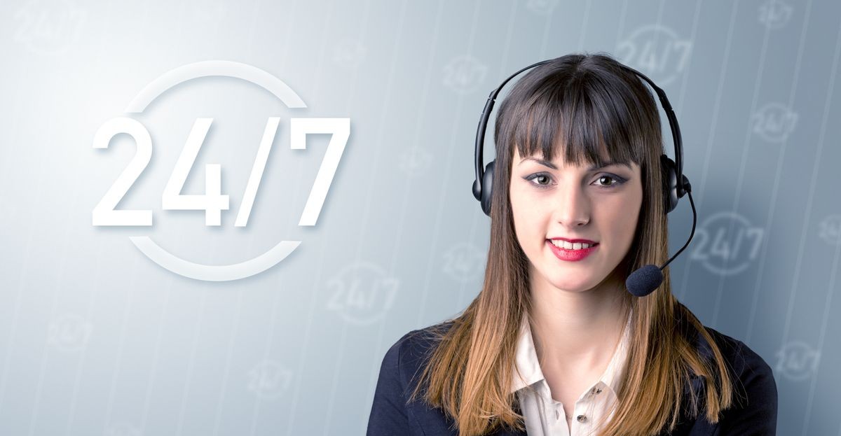 Young female telemarketer with a 24 7 sign next to her